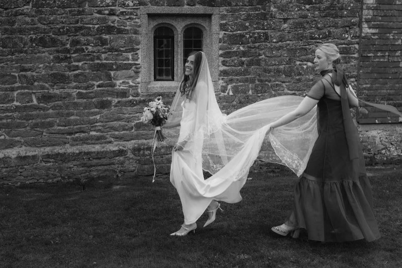 A bridesmaid carrying the veil through the courtyard